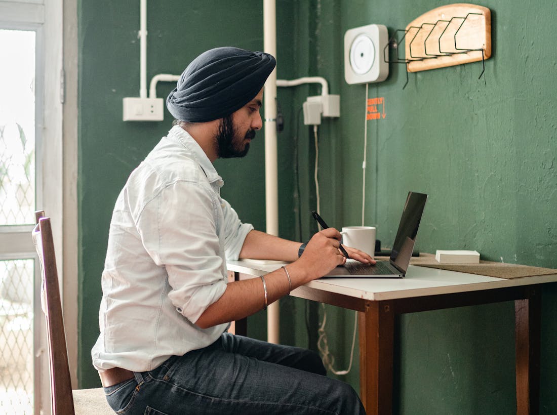 Indian freelancer working on a laptop at a wooden home-office desk