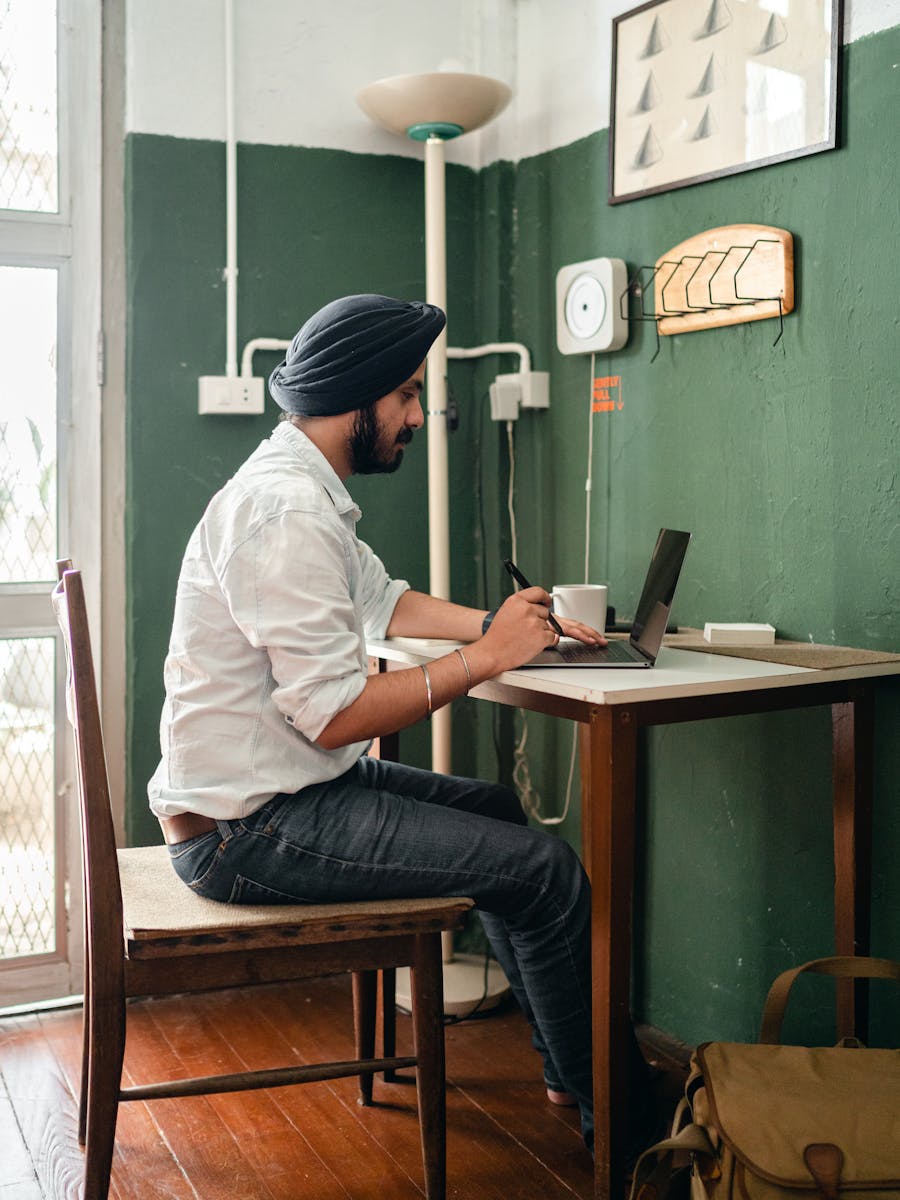 Indian freelancer working on a laptop at a wooden home desk